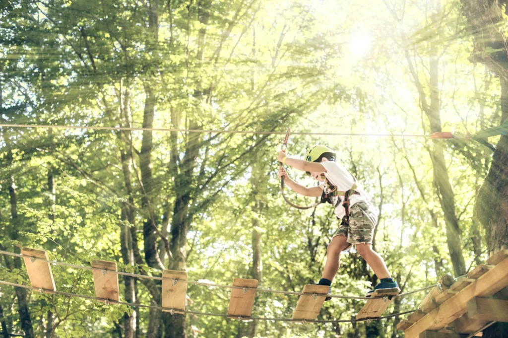 Happy Little Boy Passing The Cable Route High Among Trees, Climb